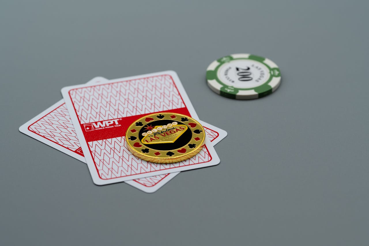 Two playing cards and poker chips, including a Las Vegas chip, on a grey background. Ideal for casino or gambling themes.