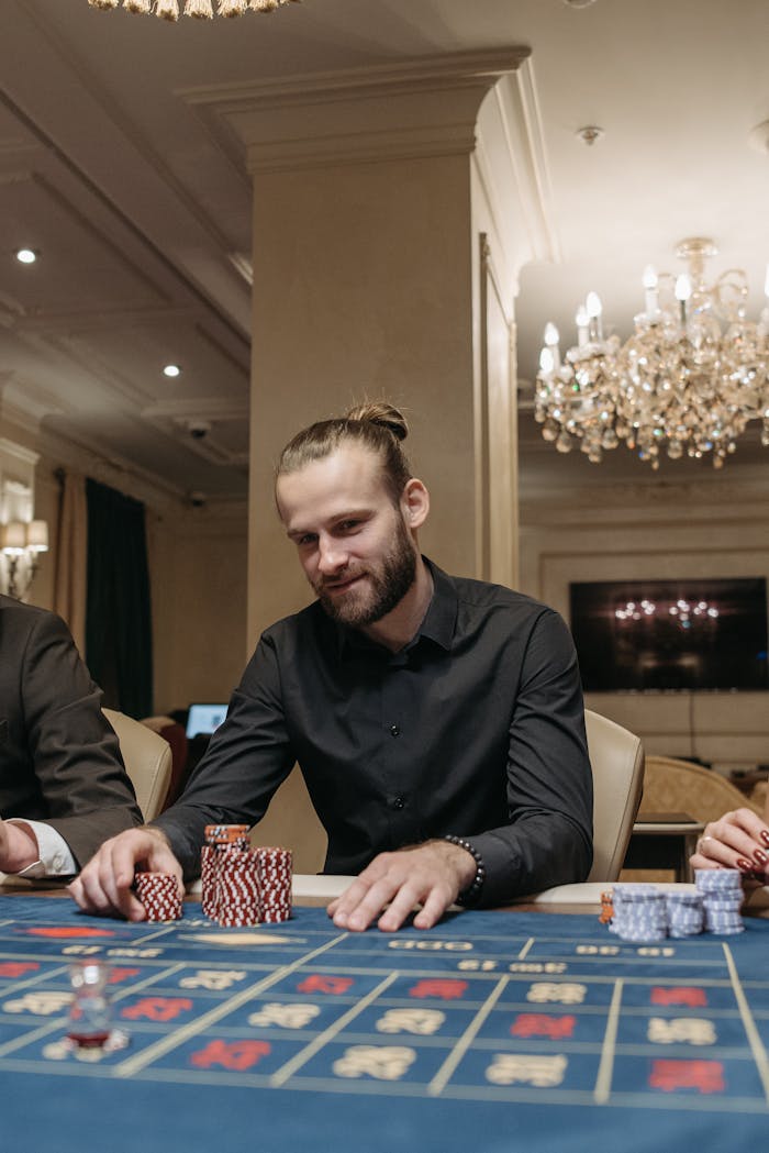 A man with a beard playing poker at a casino, focused on the game with poker chips on the table.