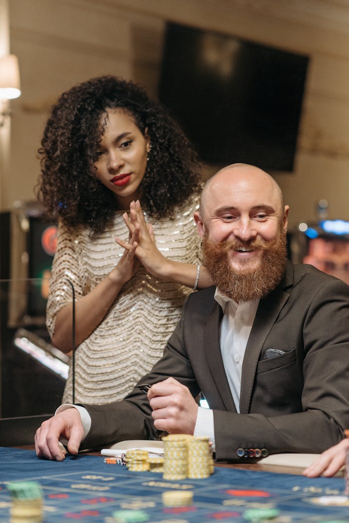 Smiling man and woman at a casino, enjoying a game with poker chips on the table.